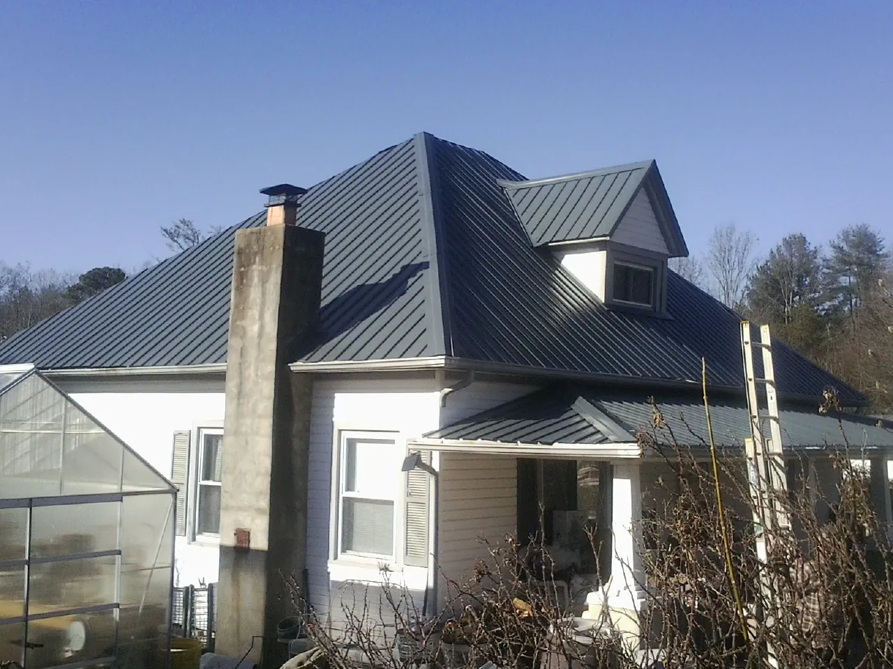 Dark blue standing seam metal roof on a white farmhouse with dormer — Slate & Tile Roof Repair by Roofing Brothers in Mosinee