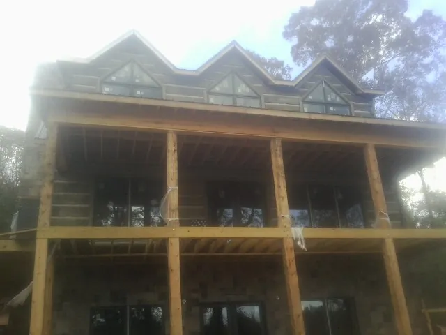 Dormers and porch framing on a large log home under construction — Roof Coating work by our crew in Mosinee
