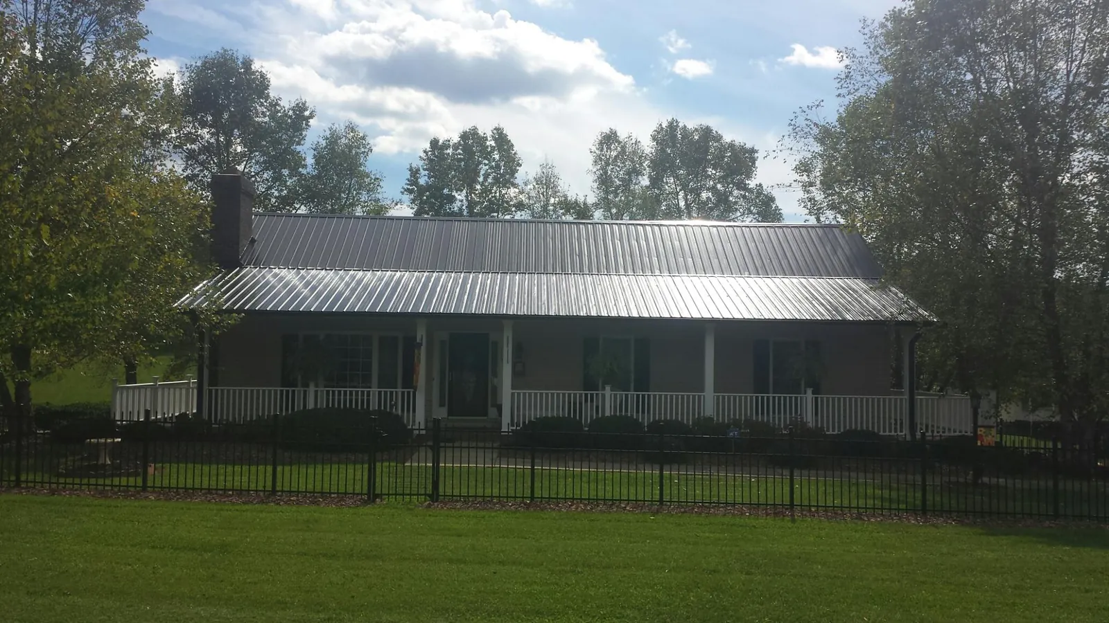 Gray metal roof on a brick ranch with a full width front porch — Gutter Guard Installation work by our crew in Mosinee