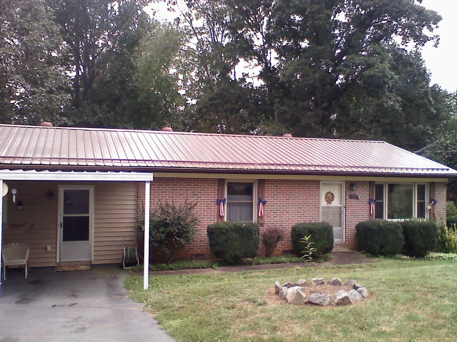 Bronze metal roof and carport on a brick ranch home — Roof Repair work by our crew in Mosinee