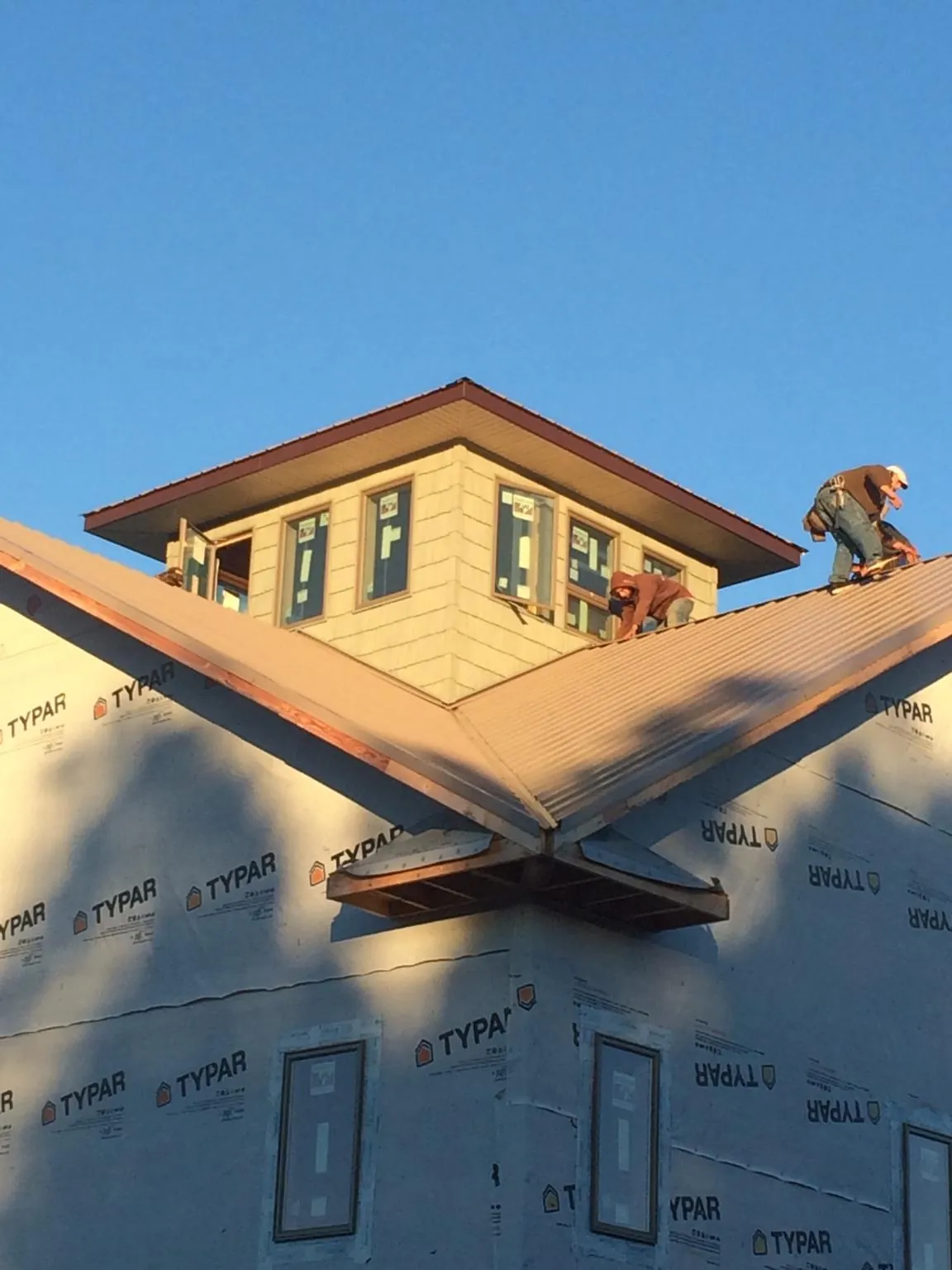 Roofers working around a rooftop cupola on a new metal roof at sunset — Roof Waterproofing in Mosinee by Roofing Brothers